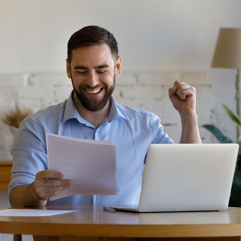 Happy young man looking at paper document feeling excited reading amazing news