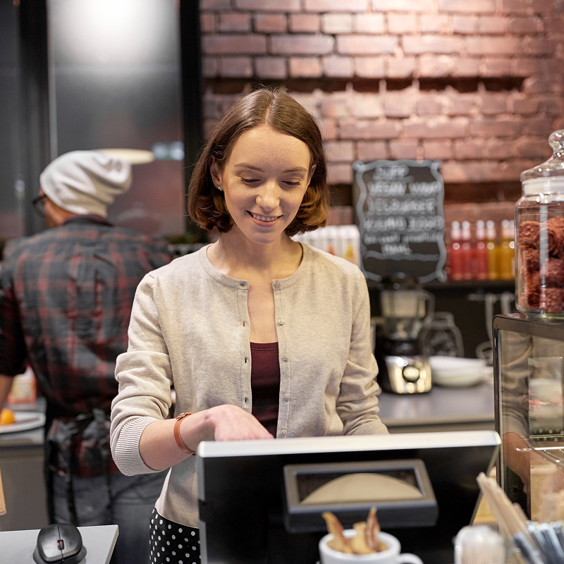 Small business people and service concept happy woman or barmaid at counter with cashbox working