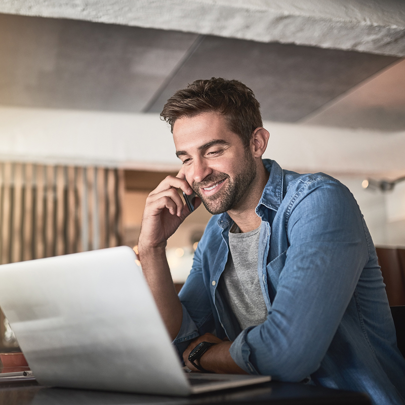 Customer support smiling man using laptop talking on phone with call center operator at home free